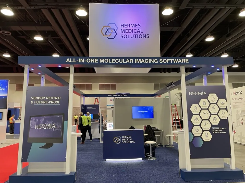 Hermes Medical Solutions exhibit with illuminated walls and meeting space