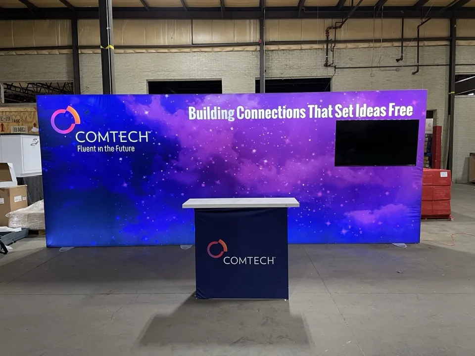 Finished exhibit with an illuminated purple video wall and reception counter