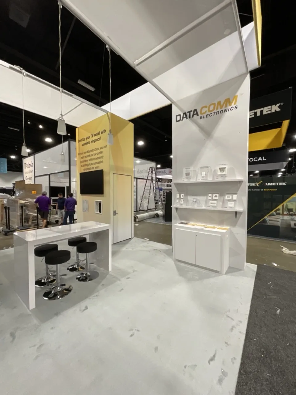 DataComm exhibit with an illuminated corner tower and meeting tables